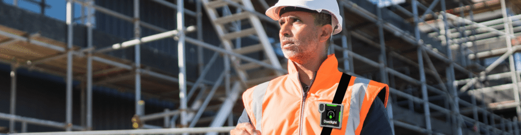 Arbeiter auf Baustelle mit Dustlight-Gerät zur Echtzeitmessung von A-Staub und Feinstaubbelastung.